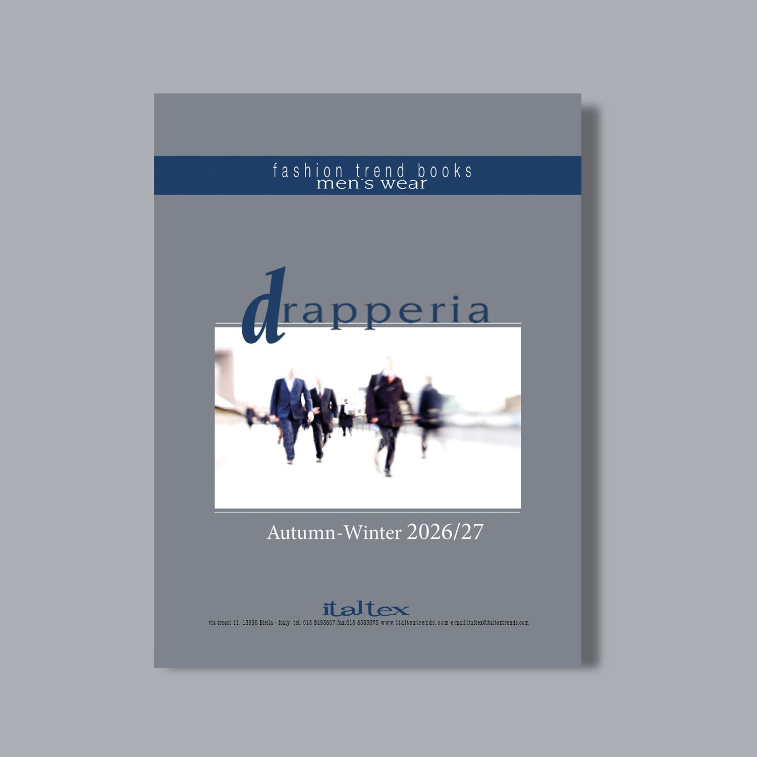 The cover of the Italtex Menswear Drapperia fashon forecast book. A light grey background with a blue band writing fashion trend books men's wear. Below it is written drapperia. Follows a picture of men walking along a street. Belo is Autumn-Winter 2026/27. The Italtex logo and the full address.